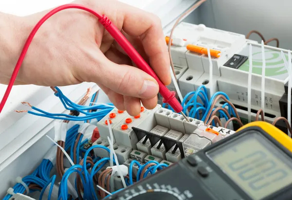 Electrician testing circuit breaker with probe